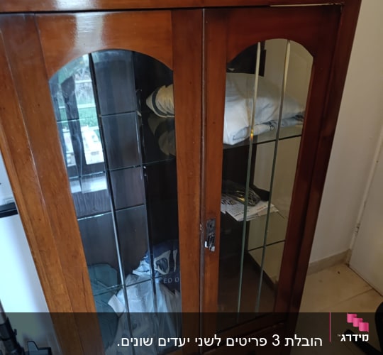 ארון עץ עם דלתות זכוכית וחפצים בפנים